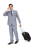 Serious businessman on the phone while holding his suitcase