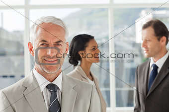 Confident businessman standing in front of colleagues speaking together