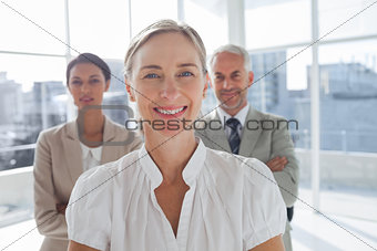 Smiling businesswoman standing in front of colleagues