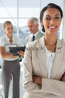 Proud businesswoman in front of colleagues working behind