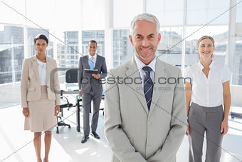 Serious businessman standing with colleagues