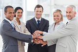 Group of smiling business people piling up their hands together