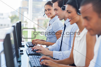 Smiling call centre employees working on computers