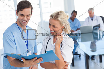 Two smiling doctors talking about a blue file