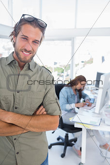 Man smiling in creative office with arms folded