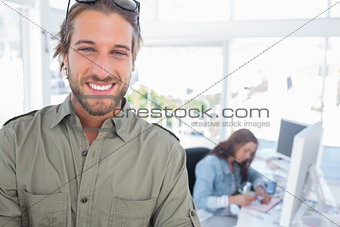 Cheerful man in creative office with arms folded
