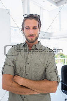 Smiling man in creative office with arms folded