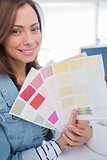 Cheerful interior designer holding up colour samples