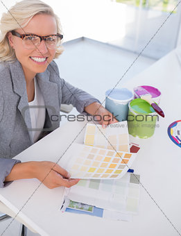 Cheerful blonde interior designer holding colour charts