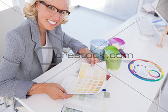 Smiling blonde interior designer holding colour charts