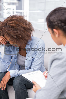 Upset woman crying on the sofa in therapy