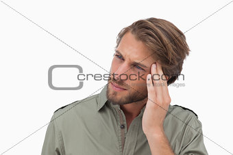 Man with headache looking away and touching his head