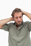 Stressed man looking down with hands on head