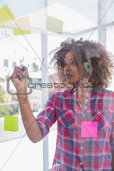 Woman with check shirt drawing on flowchart with marker