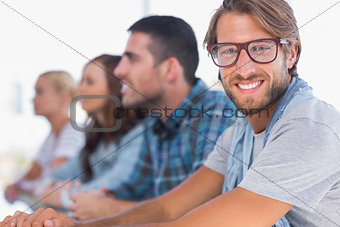 Creative team sitting in a line with one man smiling