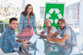Team having meeting about recycling and smiling at camera