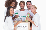 Happy volunteers putting food in donation box