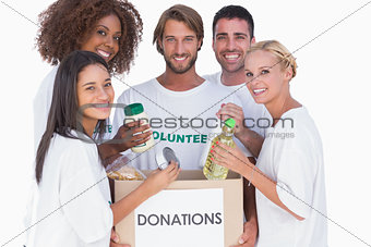 Happy volunteers putting food in donation box