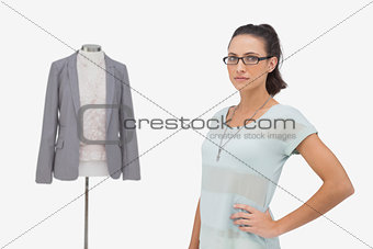 Fashion designer posing beside clothes mannequin