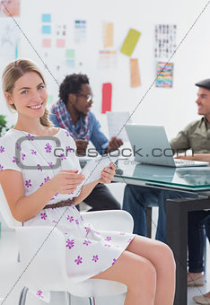 Happy woman using tablet with creative team working behind