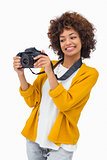 Smiling girl holding digital camera and looking at it