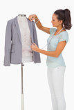 Fashion designer measuring blazer lapel on mannequin