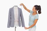 Fashion designer measuring blazer sleeve on mannequin