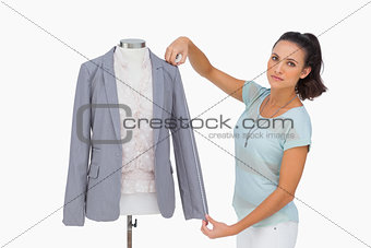 Designer measuring blazer sleeve on mannequin
