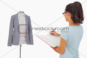 Designer looking at her mannequin and taking notes