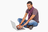 Stylish man sitting on floor using laptop