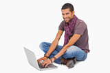Happy man sitting on floor using laptop