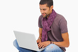 Smiling man sitting on floor using laptop