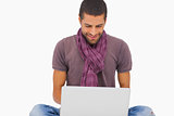 Fashionable man sitting on floor using laptop