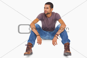 Handsome man sitting on floor and looking away
