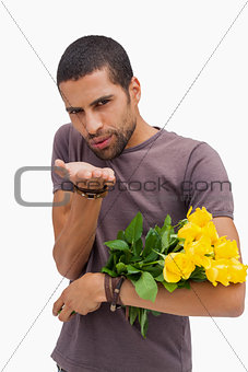 Handsome man blowing a kiss and holding roses