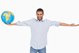 Smiling man holding out a globe and other arm outstretched