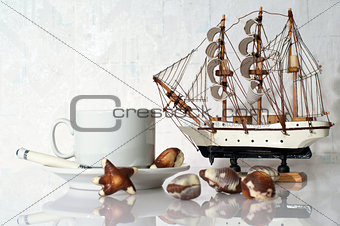 Souvenir yacht, cup and candies on white background