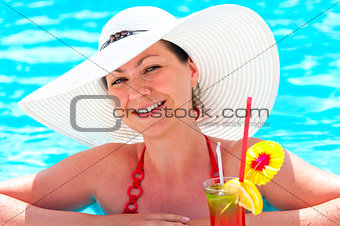 beautiful young girl in the pool with a cocktail