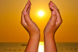 Sun over the sea in female hands