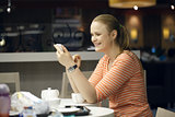Young woman chatting on smartphone in cafe.