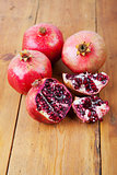 Four ripe pomegranate fruit on wooden surface
