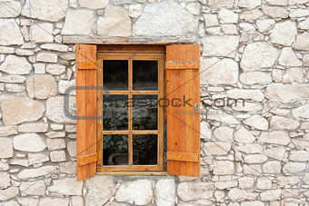 Wooden window and shutters in stone wall