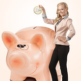 sexy business woman saving coin in money box