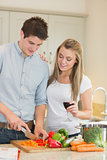 Man cutting peppers with woman drinking wine