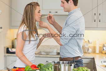 Woman tasting sauce from pot