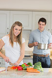 Woman cutting vegetables with man helping