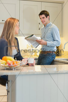 Man reading the newspaper and woman drinking