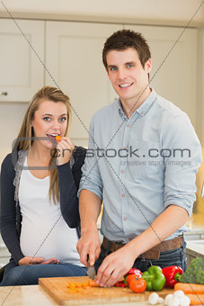 Pregnant woman eating vegetables prepared by husband