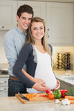 Pregnant woman and huband stand behind kitchen counter