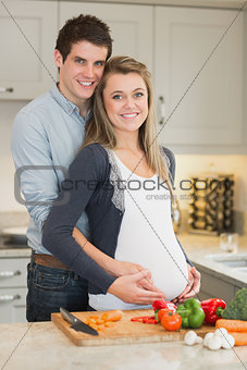 Pregnant woman and huband stand behind kitchen counter